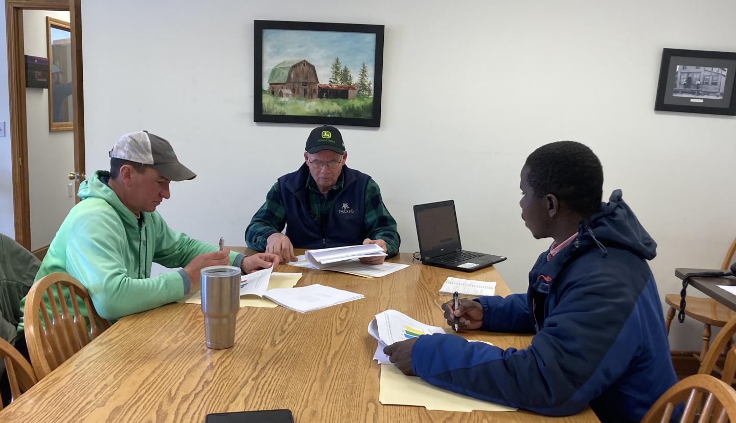 Three people sitting at table in office