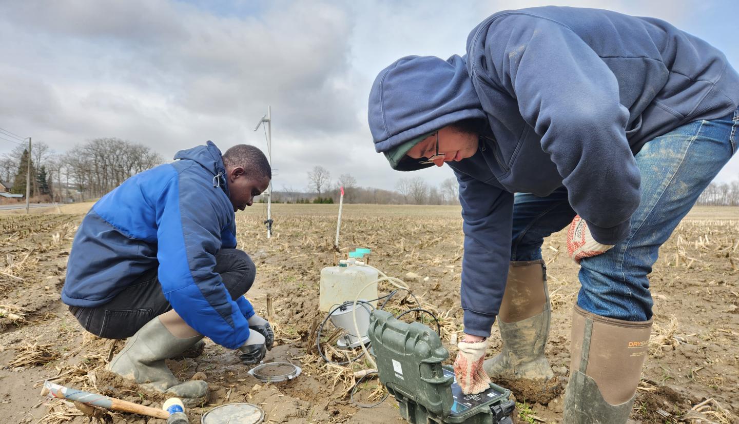 Two people conducting soil tests in field